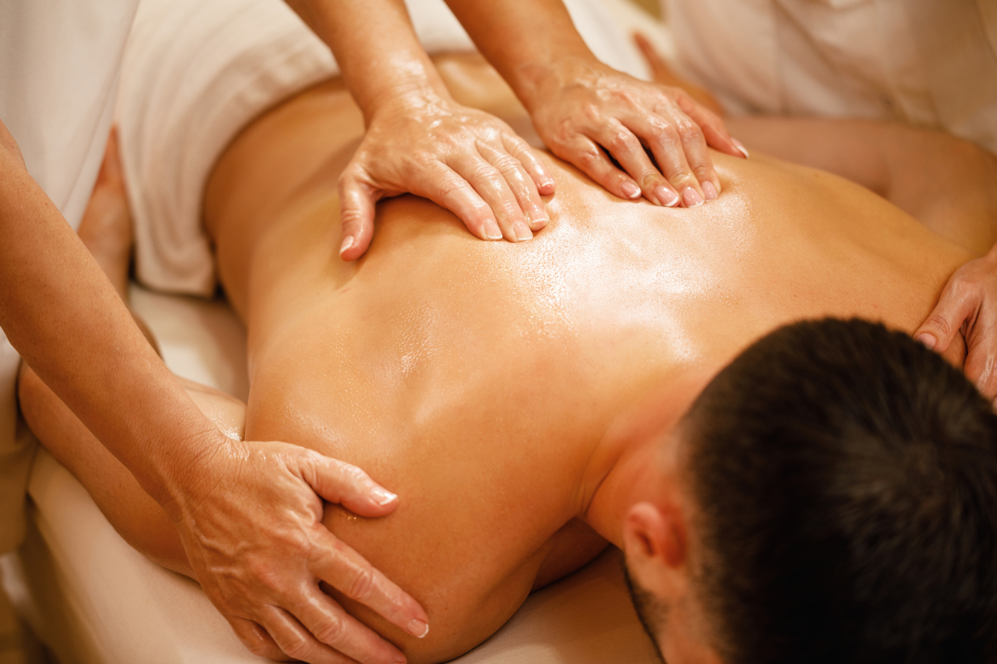 Four hands massage with two therapists working in synchronized harmony at Uniq Massage in McKinney, TX